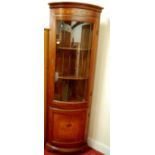 A reproduction walnut and inlaid bowfront corner display cabinet, having glazed upper door