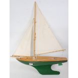 A wooden and tinplate model of a sailing yacht finished with stained deck and green and red lined