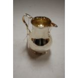 A George V silver cream jug of bell shape having a flying C scroll handle, 7.6oz