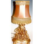 A late 20th century resin table lamp the whole surmounted by three cherubs, with silk shade,