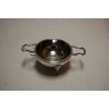 A modern silver twin handled tea strainer on stand