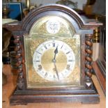 A 1920s oak cased mantel clock having an arched brass dial with silvered chapter ring and Roman