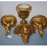 A pair of gilt painted plaster wall brackets, each in the form of a putti with outstretched arms and