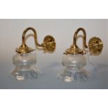 A pair of lacquered brass single sconce wall light fittings, each having a clear glass bell shaped