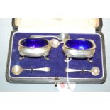 A pair of George V silver open salts of squat rectangular form with blue glass liners with two