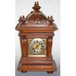 A late 19th century continental walnut cased mantel clock having a silvered dial with Roman numerals