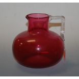 A Victorian cranberry glass water jug having a spirally turned angular handle