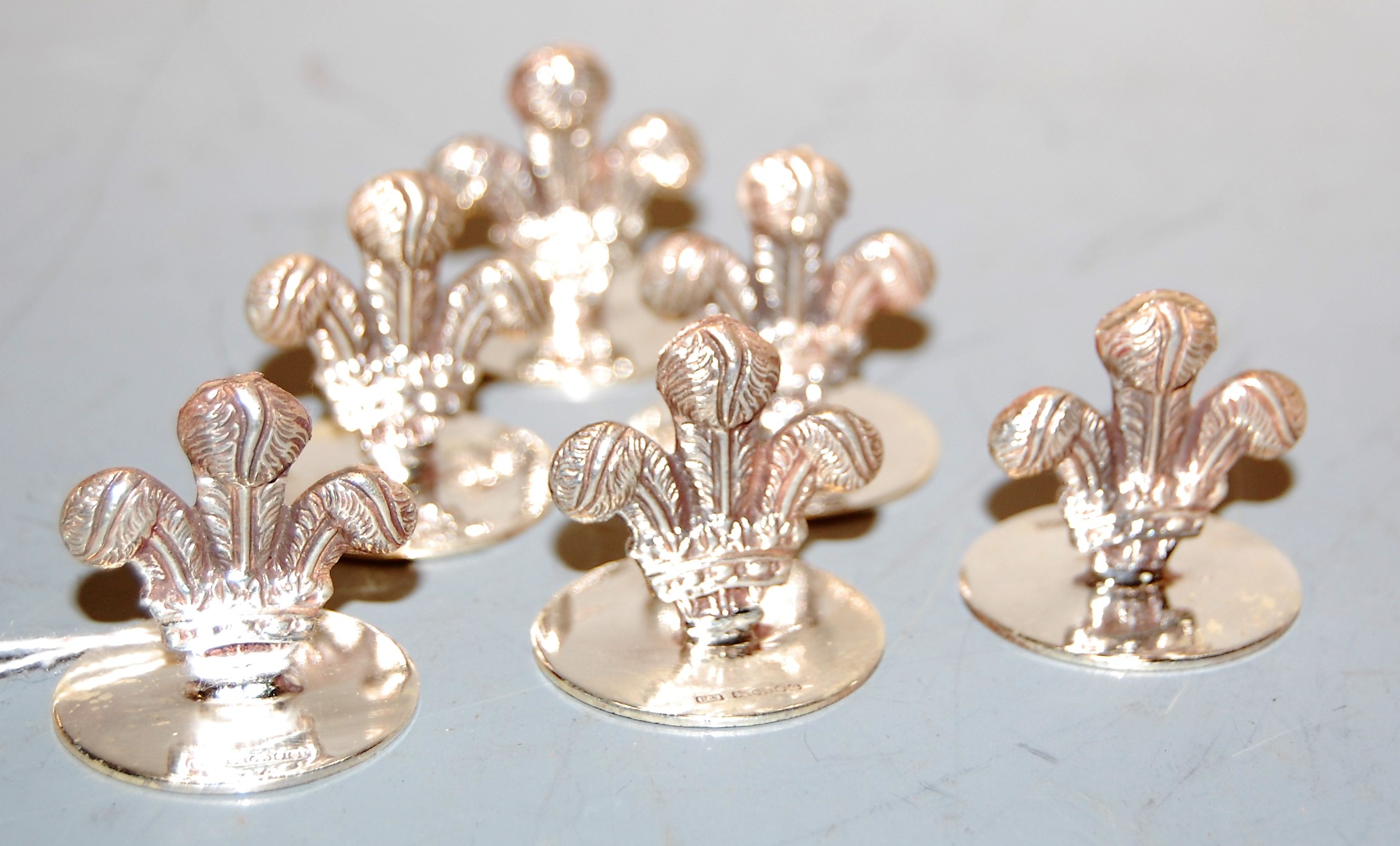 A set of six modern silver place setting holders, each in the form of a fleur de lys, maker E & J,