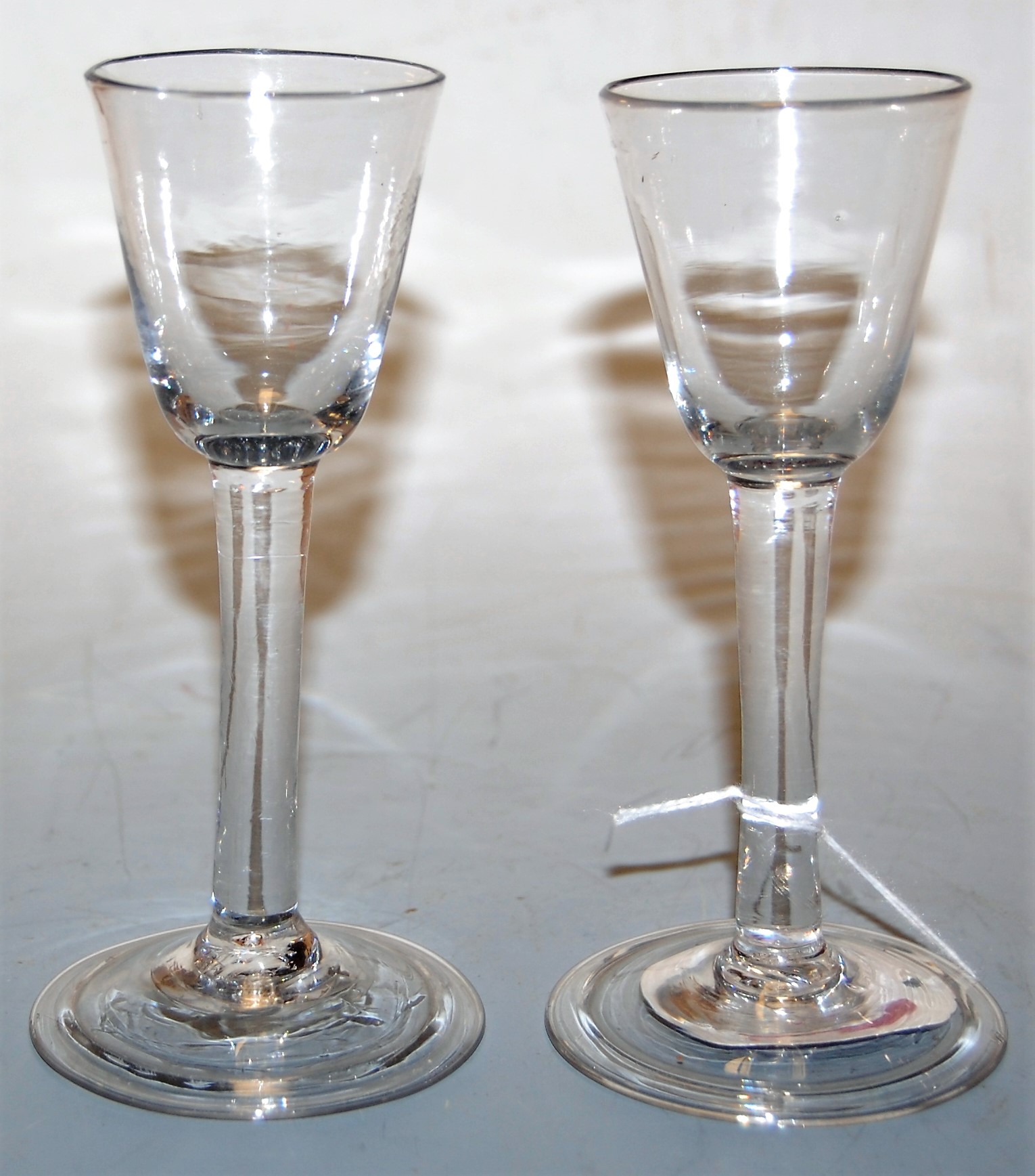 A pair of 18th century liqueur glasses, each having a bell shaped bowl to a plain stem and conical