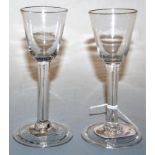 A pair of 18th century liqueur glasses, each having a bell shaped bowl to a plain stem and conical