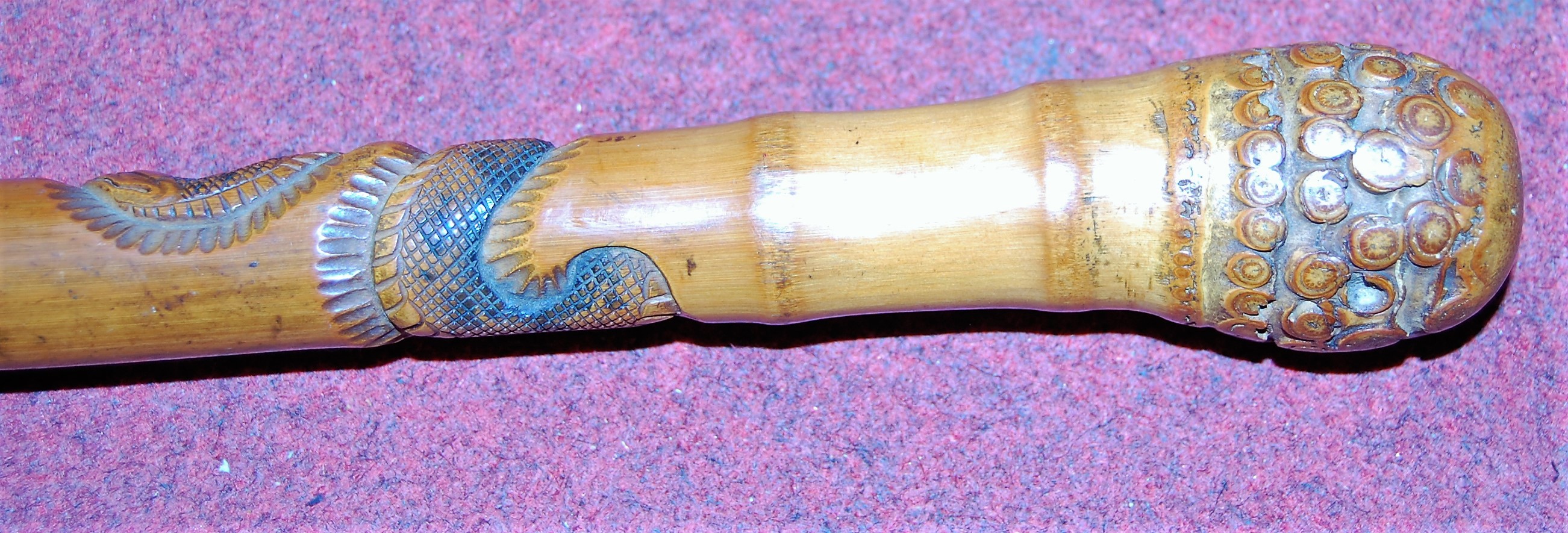 An early 20th century bamboo walking stick, carved with sinuous snakes