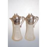 A pair of moulded glass and silver plated claret jugs