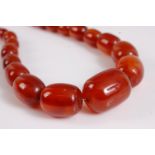 A faux amber necklace, the graduated oval beads, between approx. 6.7 - 21mm diameter, 60cm long, (