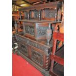 A Continental joined and heavily carved oak court cupboard, having columned and panelled back raised