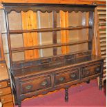 An antique joined oak long dresser, having three tier open plate rack over three frieze drawers to