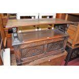 An early 20th century line carved oak twin panelled fold-over monks bench, having a hinged box