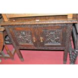 An early 20th century heavily relief carved oak double door side cupboard, width 81cm