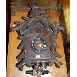 A stained and relief carved Swiss hanging cuckoo clock, with twin cast iron weights