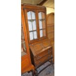 An early 20th century geometric moulded oak bureau bookcase, having twin coloured lead glazed