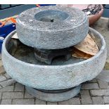 A contemporary large circular two tier water feature, with two boxes of sundry pebbles (comprised of