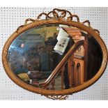 A late 19th century French gilt wood reeded and bevelled oval wall mirror having floral crested