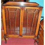 A 1930s oak ledgeback double door glazed bookcase, w.104cm