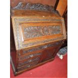 A circa 1900 heavily carved oak three-quarter gallery back slopefront writing bureau having lion