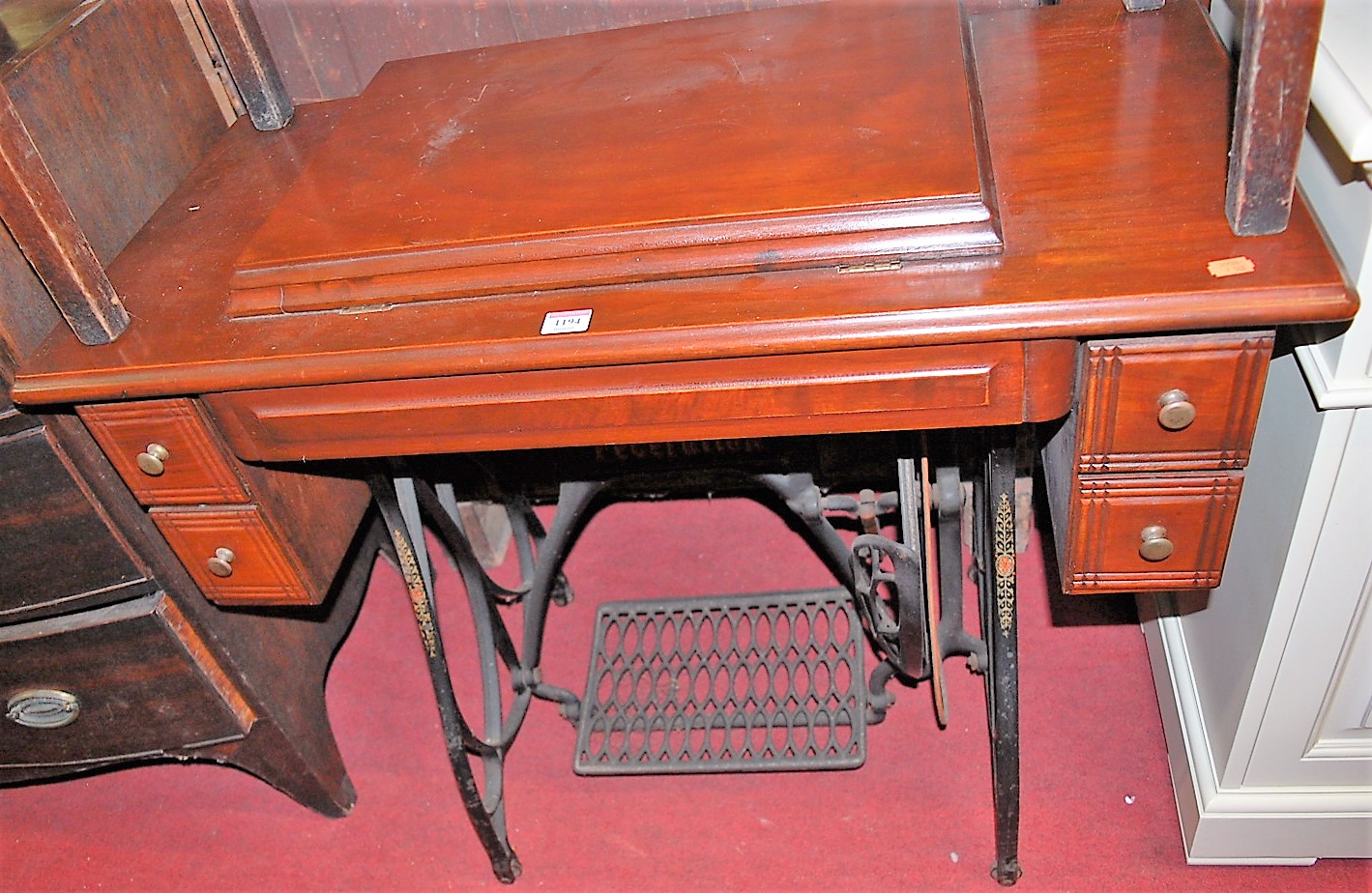 An early 20th century Federation sewing machine table, having hinged compartment and cast iron base,