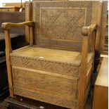 An early 20th century line and relief carved oak single fold-over monks bench, having hinged box