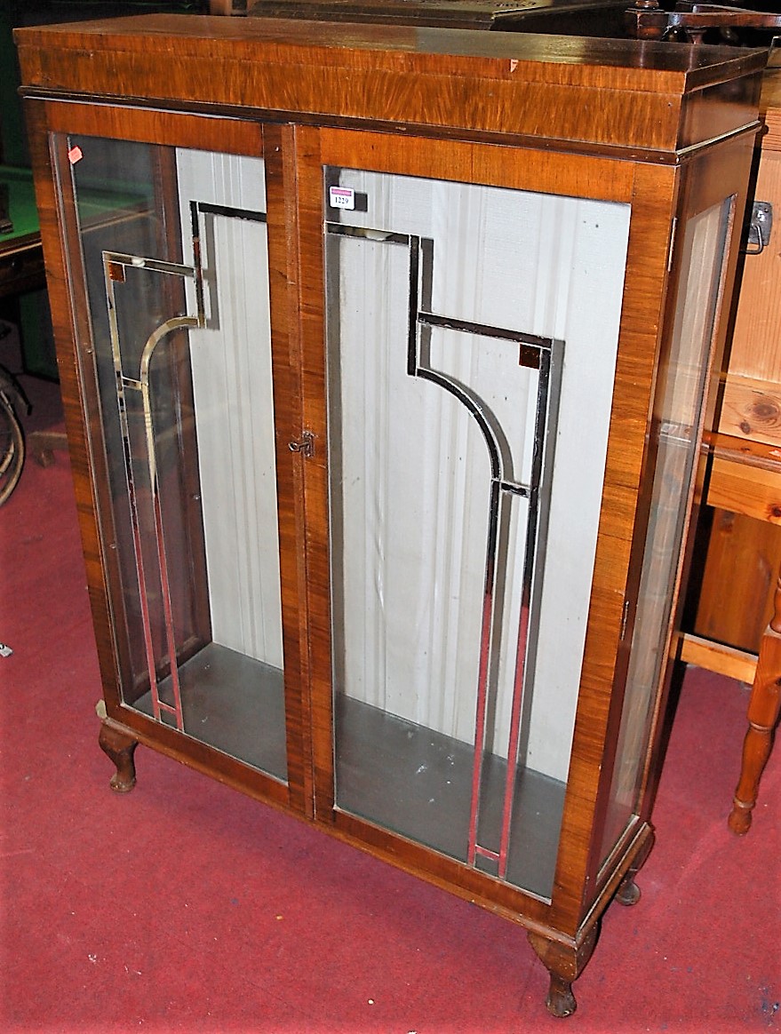 An Art Deco figured walnut double door glazed china display cabinet on squat cabriole supports,