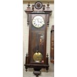 A circa 1900 Vienna walnut cased drop trunk wall clock, having a white enamel circular dial with