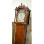 An early 19th century mahogany longcase clock, having a painted arched dial decorated with a