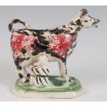 A circa 1800 Prattware cow creamer with attendant milkmaid, decorated in sponged red and black to