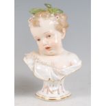 A mid-19th century Meissen porcelain bust, modelled as a child with leaves and flowers in its