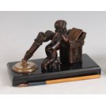 A circa 1900 French bronze desk stand, modelled as a kneeling cupid reading a book at a desk, with