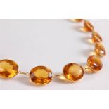 A citrine riviere necklace, the oval spectacle set citrines, approx. 14 - 16mm long, each joined