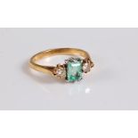 An 18ct three stone emerald and diamond ring, the central emerald cut emerald set with a round
