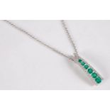 An 18ct emerald and diamond pendant, the tapered lightly curved pendant set with six graduated round