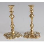 A pair of mid-18th century brass taper sticks, having multi-knopped columns to petal bases, h.12cm`