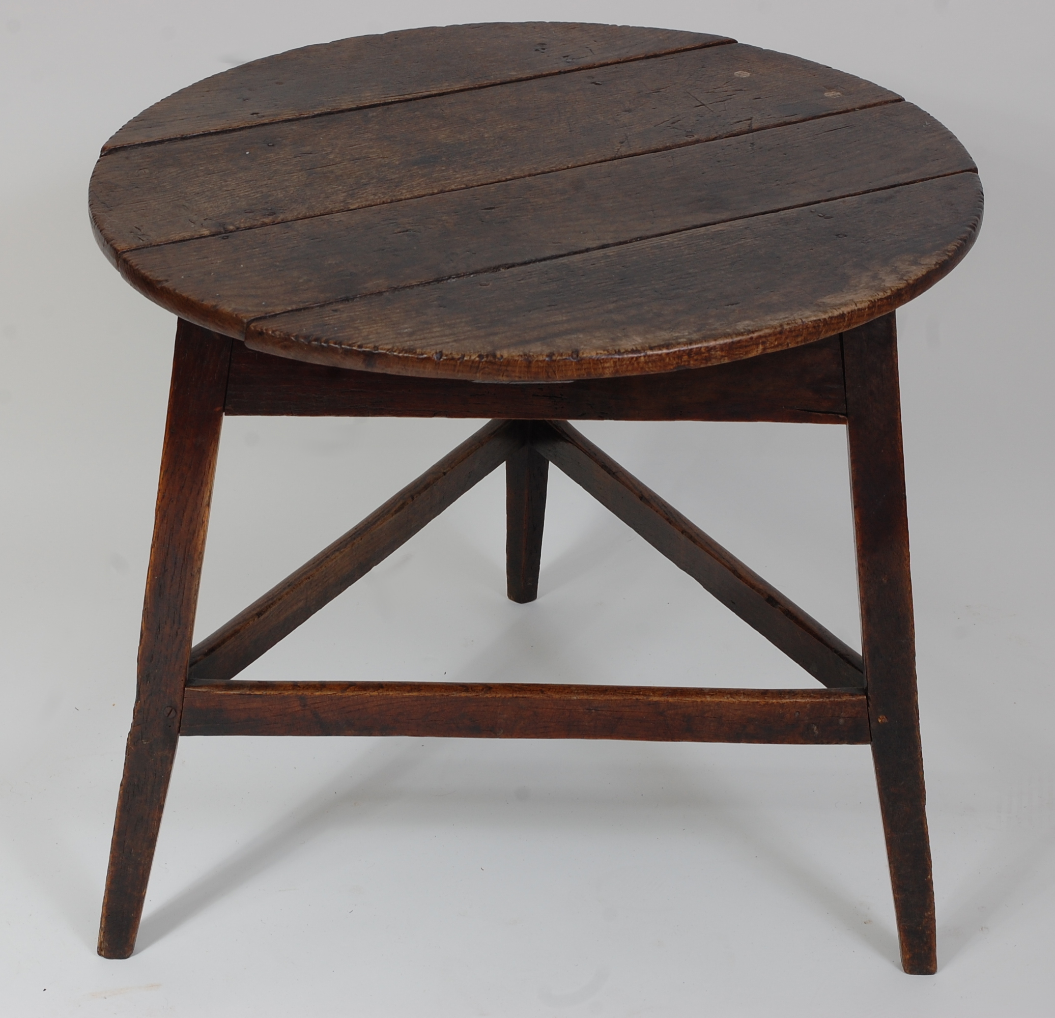 An 18th century oak cricket table, the circular four-plank top above a plain frieze, on typical base