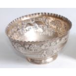 A circa 1900 Chinese white metal bowl, having a wavy rim above an embossed border depicting