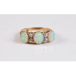 An 18ct three stone opal and diamond ring, the three oval opal cabochons interspaced with two