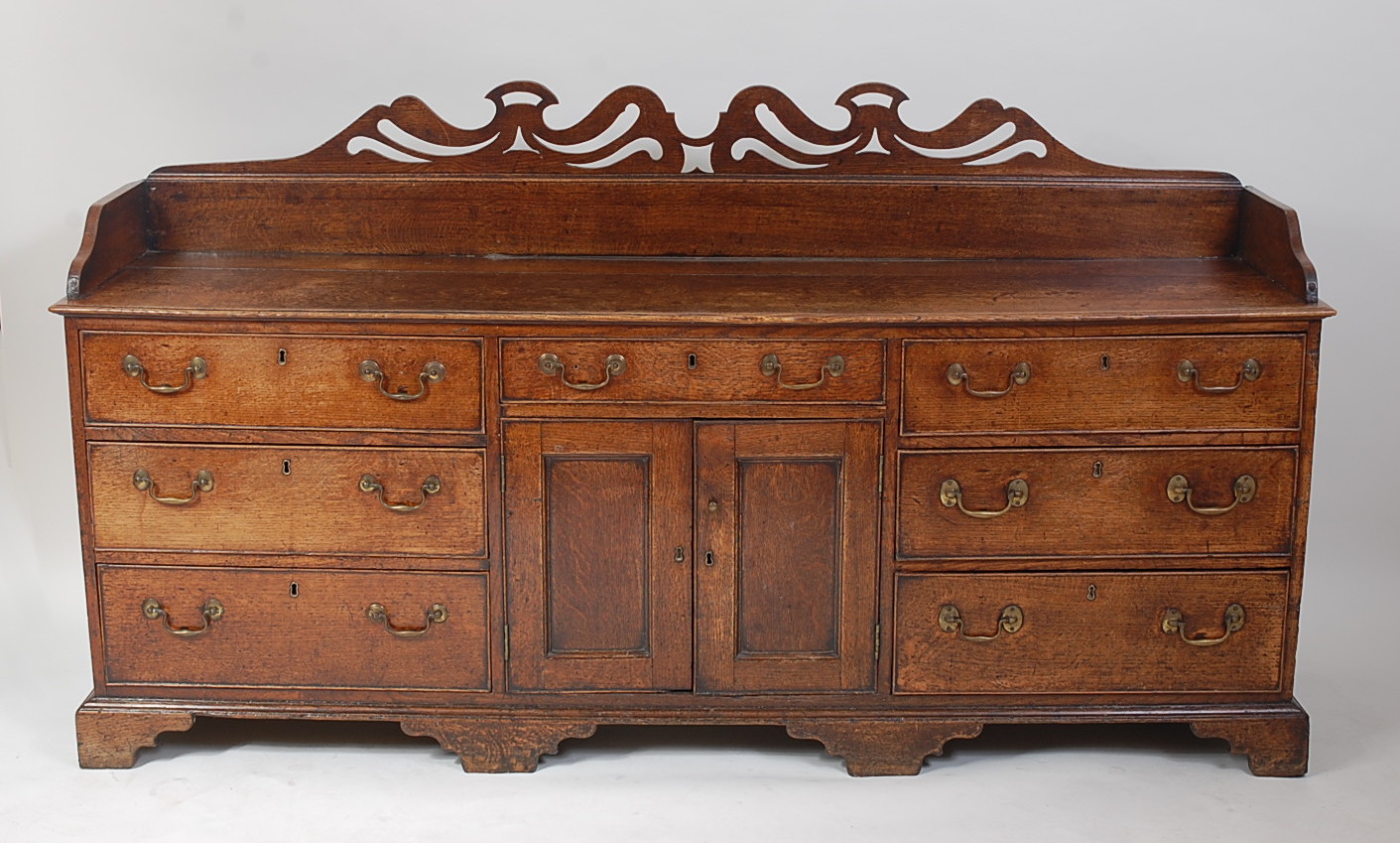 A George III oak Lancashire dresser, having a three-quarter gallery with pierced frieze, over an