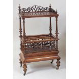 A Victorian figured walnut canterbury whatnot, having fret carved three-quarter gallery and secret