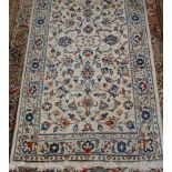 A Persian woollen Kashan rug, the cream ground decorated with scroll flowers and foliage, 133 x