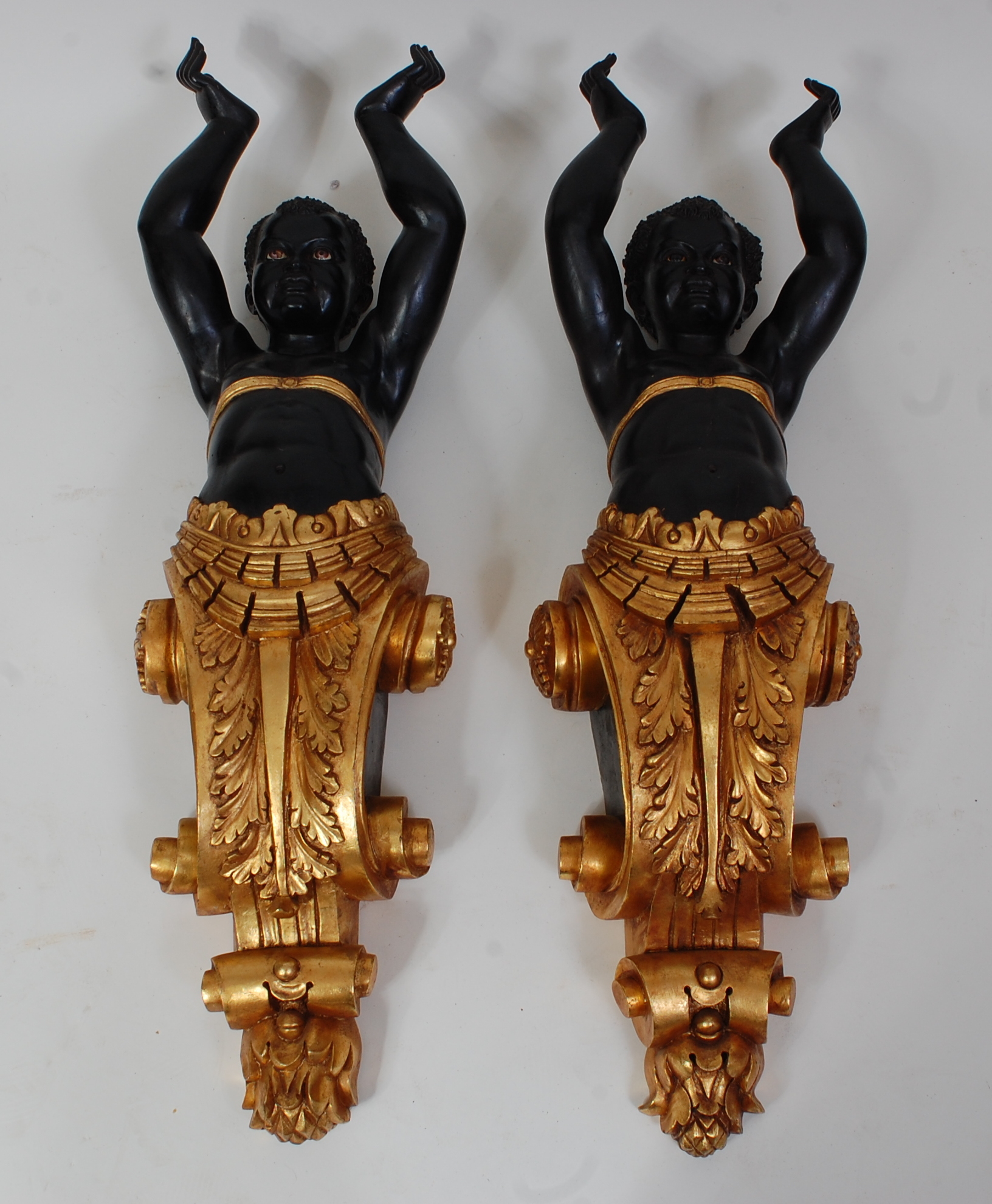 A pair of contemporary Blackamore carved wooden corbels, each in the form of a boy with arms