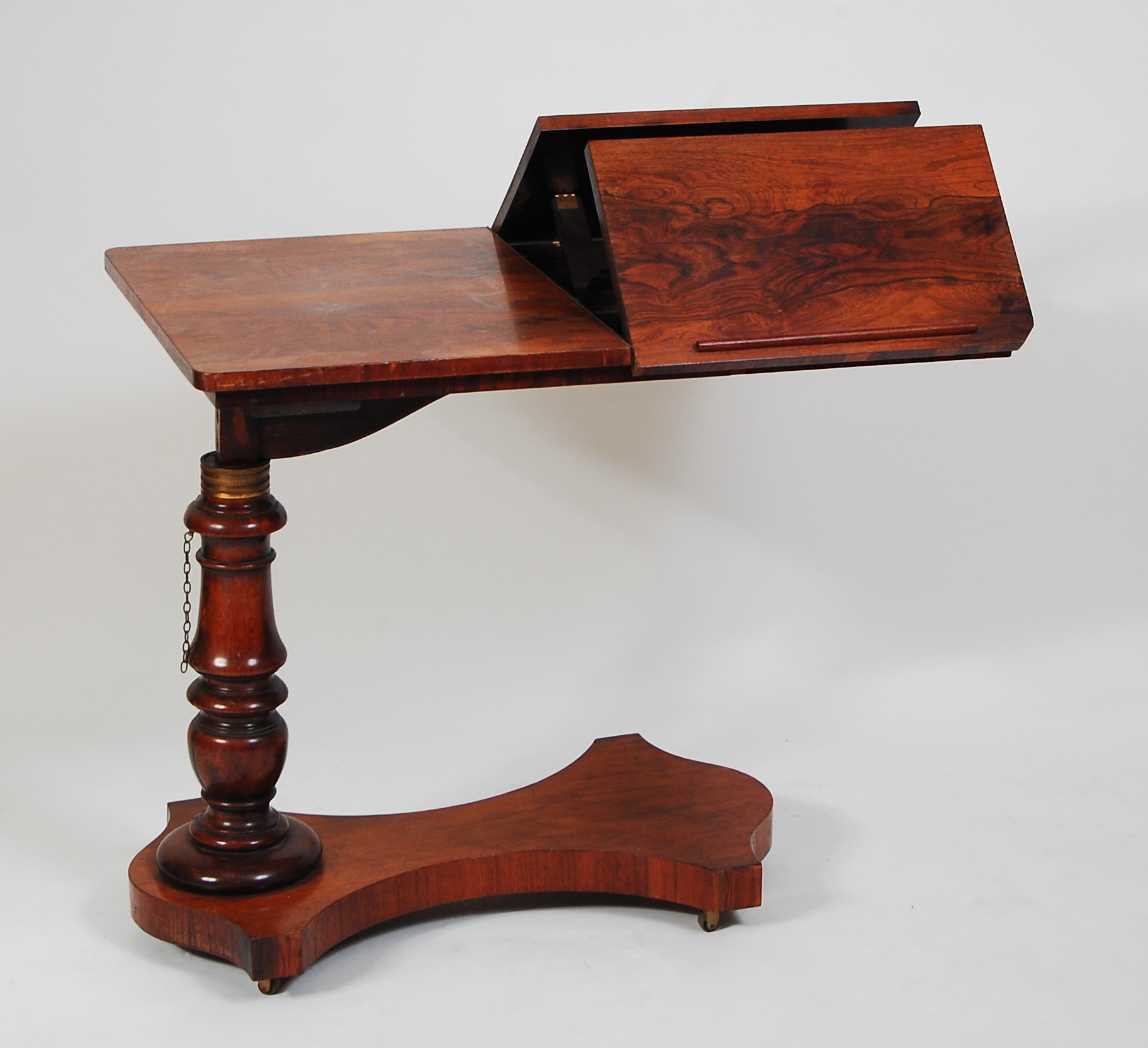 A Victorian rosewood bed table, having rise-and-fall action, hinged bookrest to platform base on