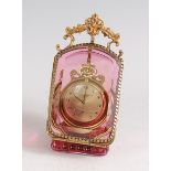 A circa 1900 cranberry glass watch holder, having gilt metal mounts and bevelled clear glass hinge