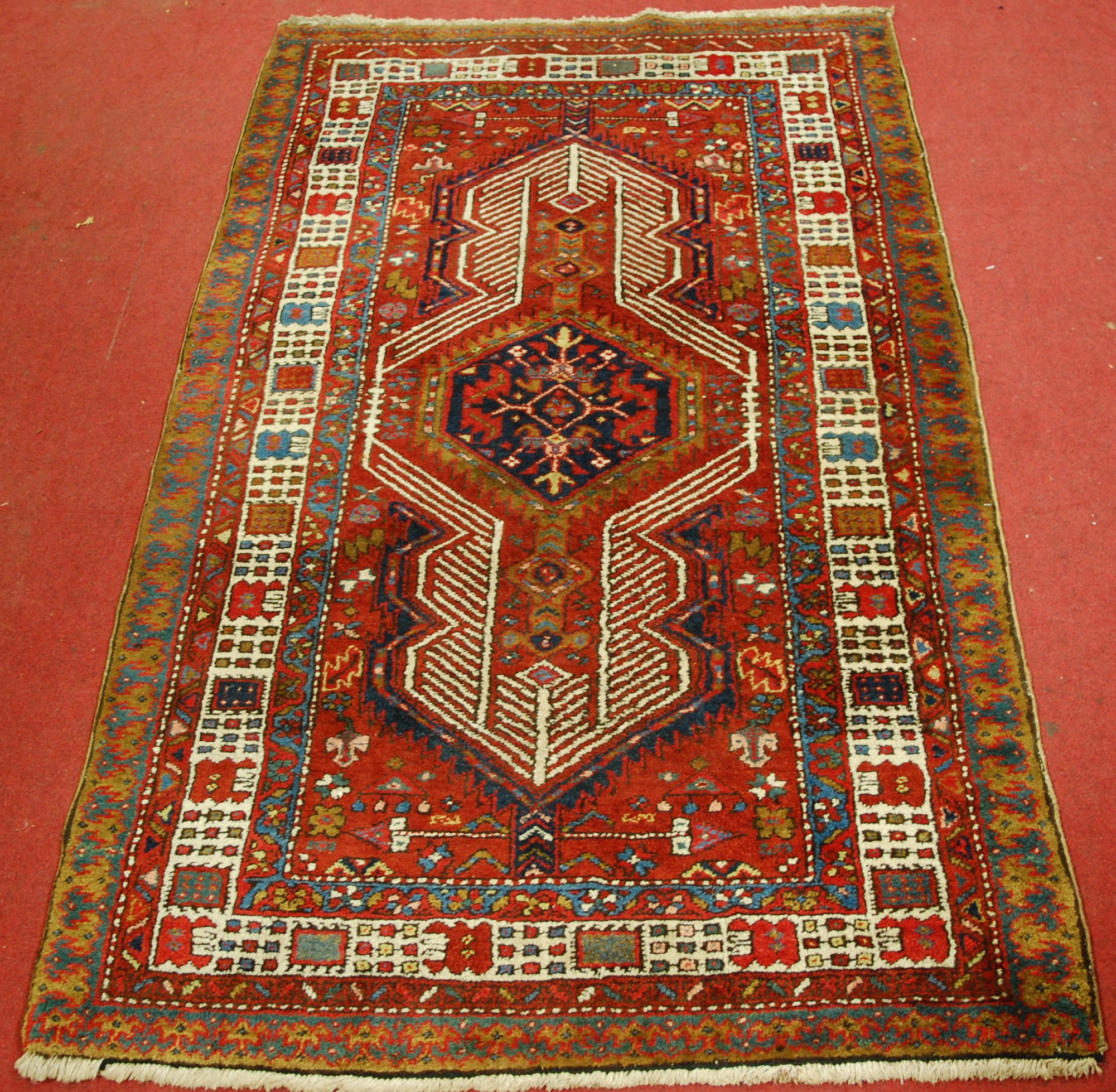 A Persian woollen Sarab rug, having a red ground decorated with central medallion and stylised