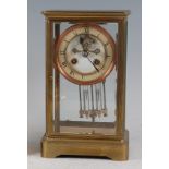 A circa 1900 brass cased four glass mantel clock, having white enamel chapter ring (heavily crazed),